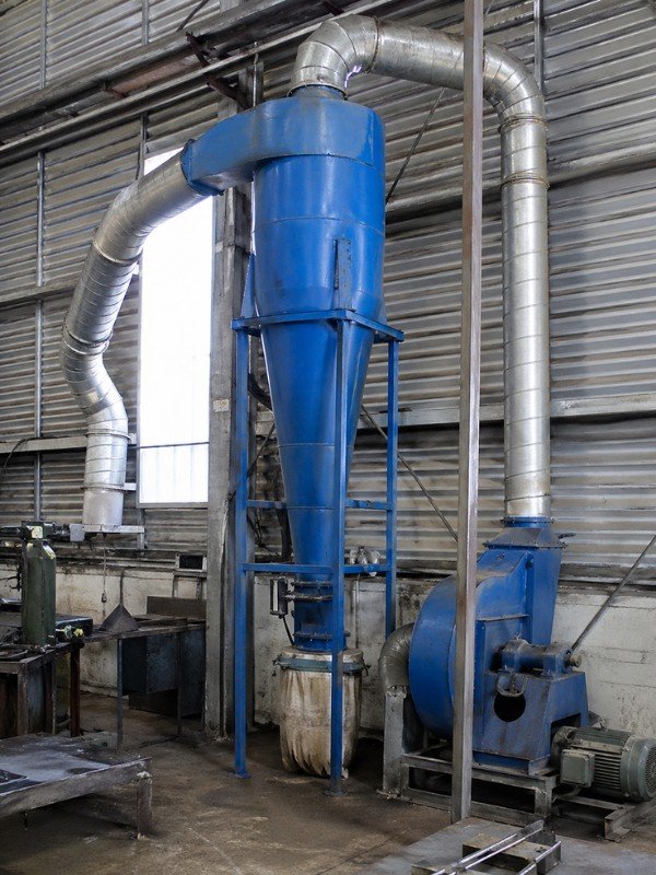 Cyclone dust collector installed in an industrial workshop with connected ducting and discharge system