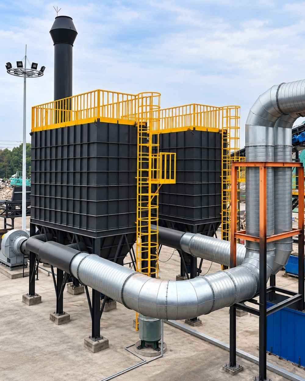 Industrial baghouse dust collector system with dual filter housings, yellow access platforms, and steel ductwork